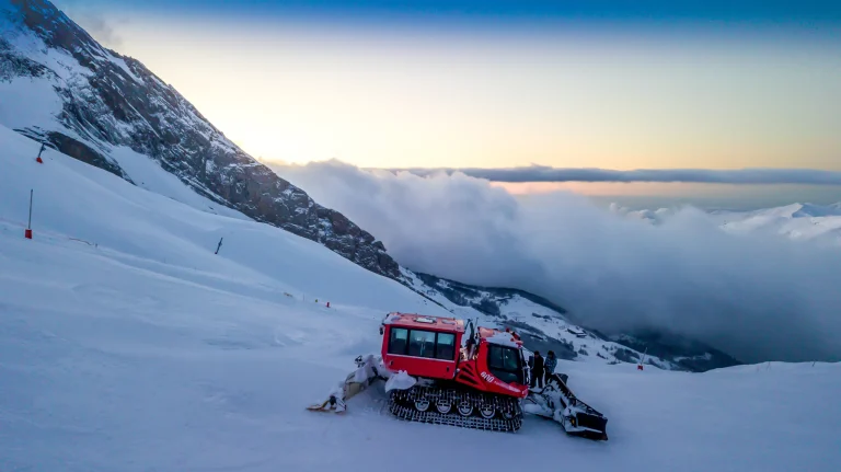 Photo aérienne par drone d'une dameuse sur les pistes de Gourette au lever du soleil